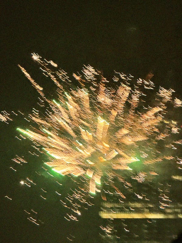 Motion blur photograph of golden fireworks bursting against a dark night sky